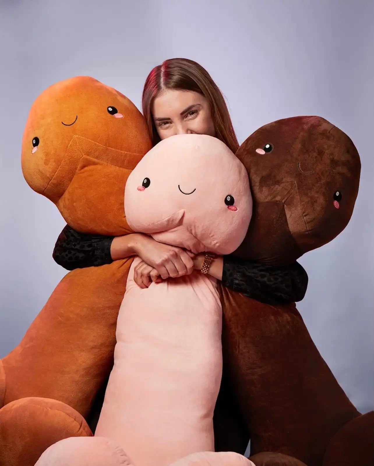 Woman hugging three phallic plush toys.